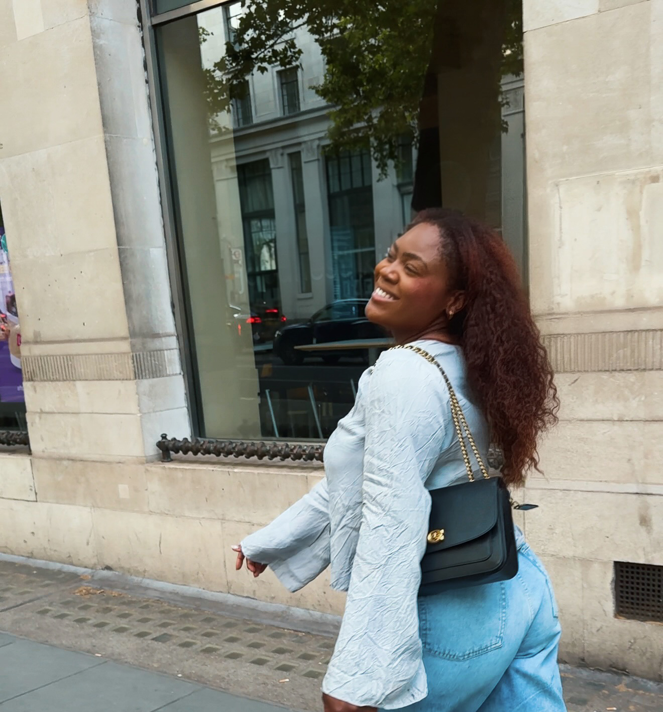 Rita walking down a London street, smiling over her shoulder